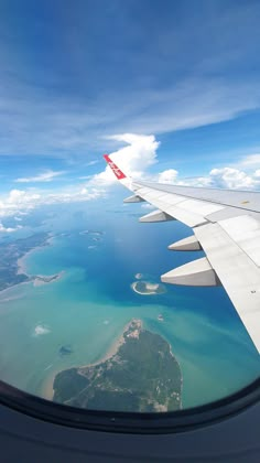 an airplane wing flying over the ocean and land