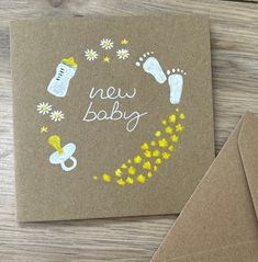 a new baby card with yellow flowers and footprints on it next to a brown envelope