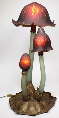 three lamps sitting on top of a leaf covered base