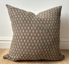 a brown and white pillow sitting on top of a wooden floor next to a wall