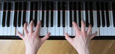 two hands are playing the piano on top of a wooden floor with black and white keys