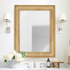 a bathroom sink with a mirror above it and flowers in a vase on the counter