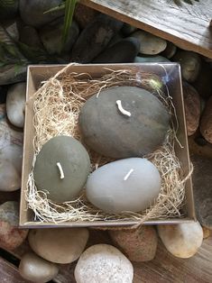 three candles sitting in a box on some rocks