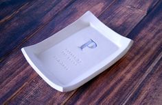 a white porcelain dish on a wooden floor with the letter p in it's center