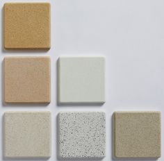 six square tiles arranged in different colors on a white surface, each with speckled edges