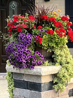 colorful flowers are growing out of a brick planter