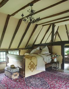 a bed sitting under a chandelier in a bedroom next to a rug and window