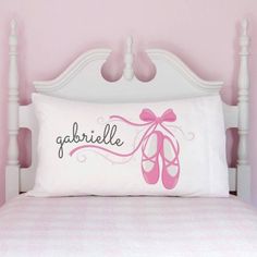 a bed with a pillow that says gabrille on it and a pair of ballet shoes