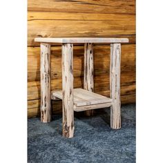 a small wooden table sitting in front of a log wall