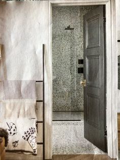 an open door leading into a bathroom next to a sink and shower stall with towels on the floor