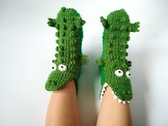 someone wearing green crocheted alligator slippers with eyes and nose on their feet