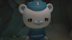 a white teddy bear with a blue hat on it's head sitting in front of a cave