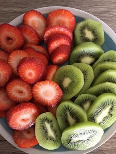 sliced kiwis, strawberries and oranges in a bowl on a table