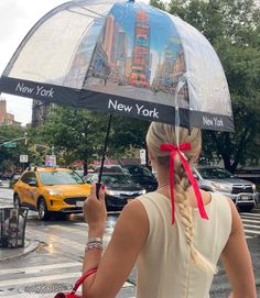 a woman is holding an umbrella with new york and new york on it in the rain