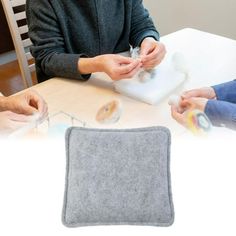 two people sitting at a table with doughnuts in front of them and one person holding something