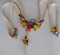 three braided necklaces with colorful flowers on them