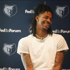 a man with dreadlocks sitting in front of a microphone and smiling at the camera