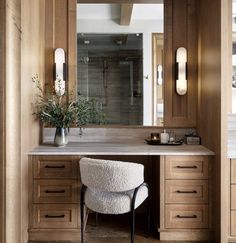 a bathroom vanity with a stool and large mirror above it, surrounded by wooden cabinets