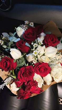 a bouquet of red and white roses sitting on top of a car seat