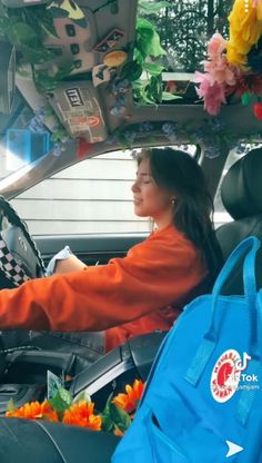 a woman sitting in the back seat of a car with flowers on her head and hands up