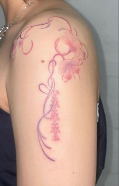 a woman's shoulder with flowers and vines on the back of her left arm