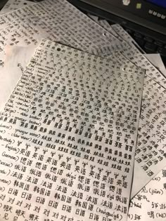 several pieces of paper with chinese writing on them sitting next to a laptop computer and keyboard