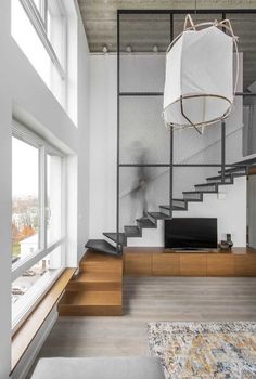 a living room filled with furniture and a large window next to a stair case in front of a flat screen tv