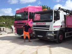 a man standing next to two pink trucks