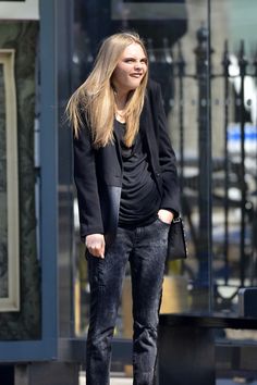 a woman in black jacket and jeans walking down the street