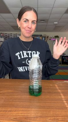 a woman sitting at a table with a water bottle in front of her