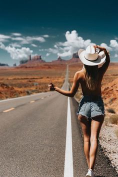 a woman walking down the middle of an empty road