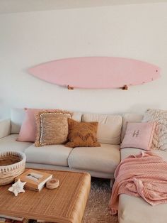 a living room filled with furniture and a pink surfboard on the wall above it