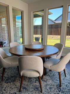 a dining room table surrounded by chairs in front of large windows with sliding glass doors