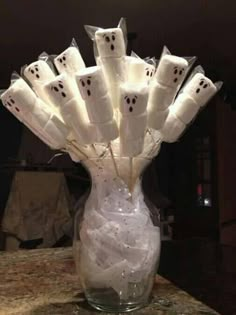 a glass vase filled with marshmallows and ghost faces on it's sides