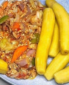 a plate filled with vegetables and rice next to pickles on a blue table cloth