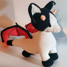 two knitted toy animals sitting next to each other on a white surface with one stuffed animal in the shape of a bat