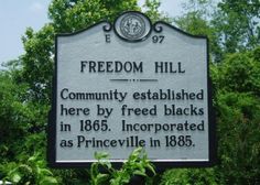 a sign in front of some trees that says, freedom hill community established here by fried black's in 1865 incorporated as princeville in 1876