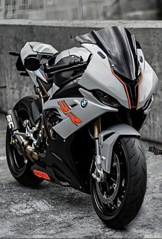 a silver motorcycle parked on top of a cement floor next to a wall with graffiti