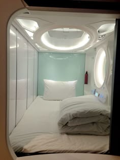 there is a bed with white sheets and pillows in the room that looks like an airplane