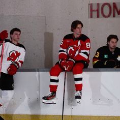 two hockey players are sitting on the bench and one is holding his hands behind his back