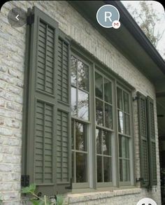 a brick house with green shutters and windows