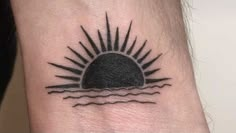 a small sun tattoo on the wrist with water and waves in it's center