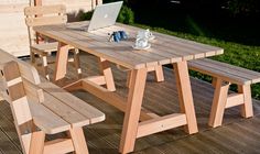 a wooden table with two benches and a laptop on it