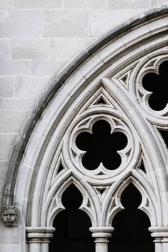 an arched window with four leafed design on the side of a stone building in black and white