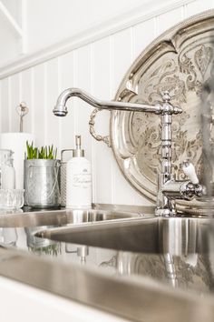 a kitchen sink sitting under a mirror next to a faucet and soap dispenser