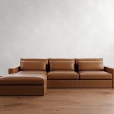 a brown leather couch sitting on top of a wooden floor next to a white wall