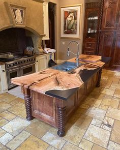 a large kitchen island made out of wood with an oven and sink in the background