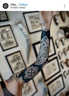 a person with a tattoo on their arm and arms in front of a wall full of pictures