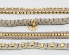 four different types of bracelets with gold beads and heart charm on each one strand