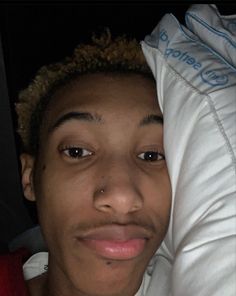 a young man is holding his head up against the back of a white pillow and smiling at the camera